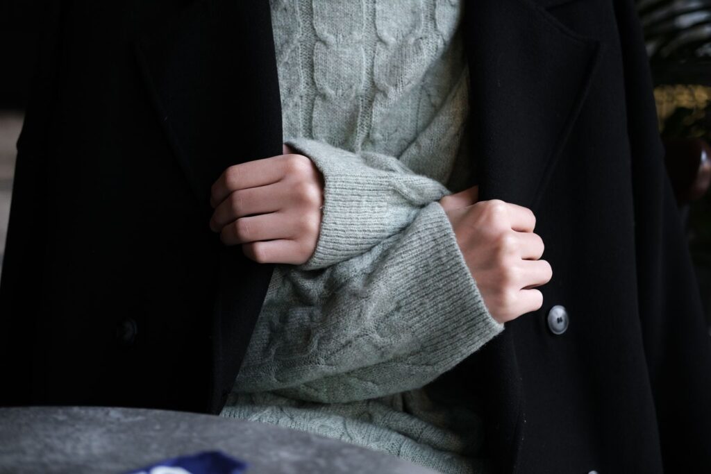 knit sweater layered under a black wool coat